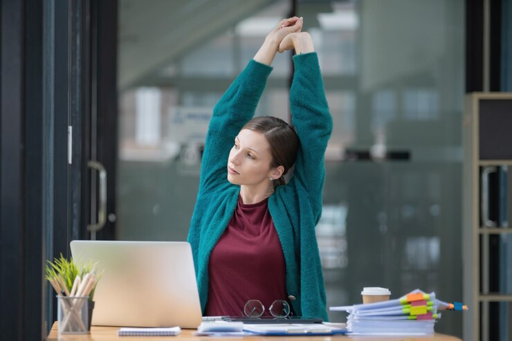 Piękna bizneswoman rozciągając ręce w biurze