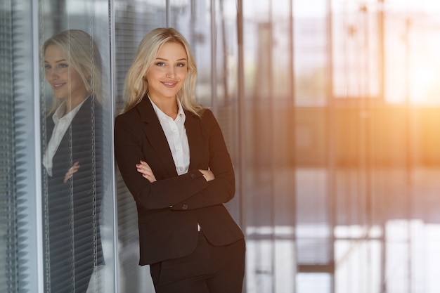 Piękna bizneswoman uśmiecha się z założonymi rękami w biurze