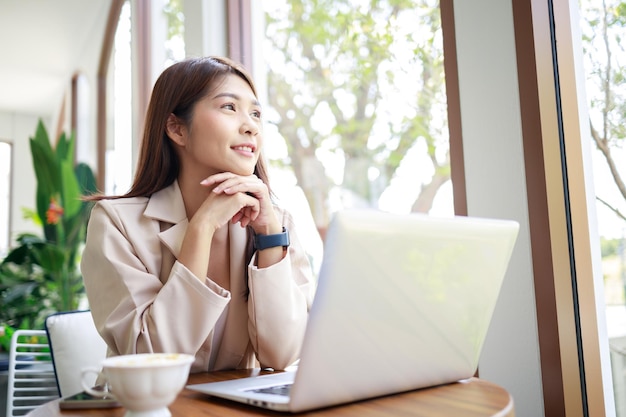 Piękna bizneswoman uśmiechnięta i pracująca przy laptopie w kawiarni