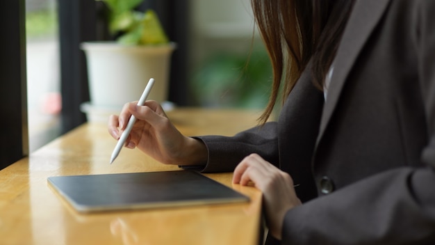 piękna bizneswoman w czarnym garniturze robi notatki na cyfrowym tablecie rysikiem