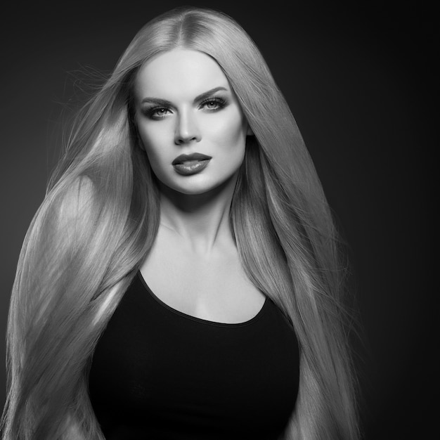 Piękna blond kobieta fryzura długie gładkie kręcone włosy moda makijaż. Strzał studio. Monochromia. Czarny i biały. Szary.