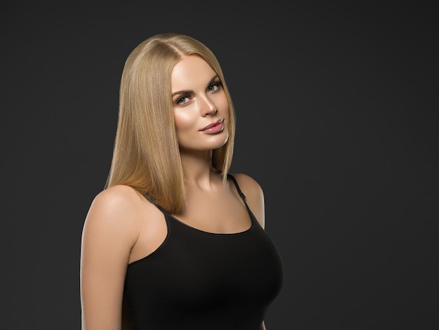 Piękna blond kobieta fryzura długie gładkie kręcone włosy moda makijaż. Strzał studio.