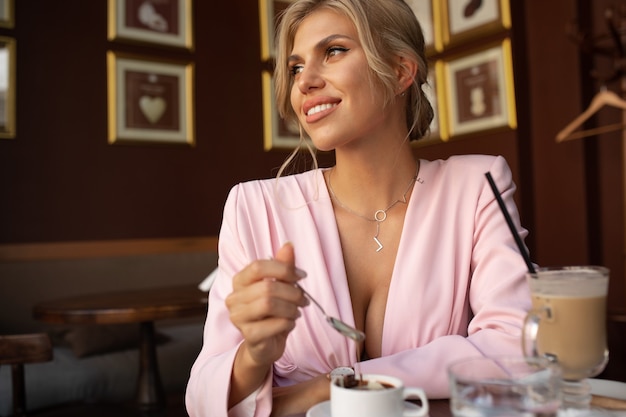Piękna blond kobieta siedzi w kawiarni