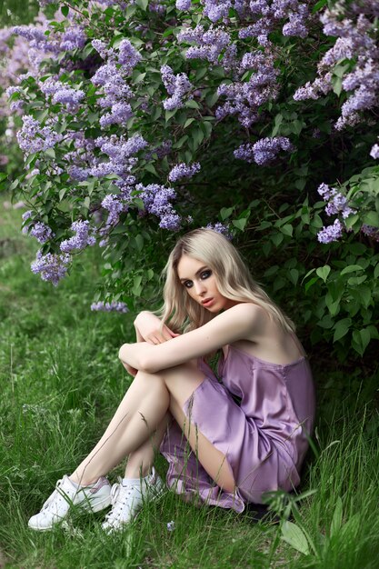 Piękna blondynka latem w liliowym krzewie