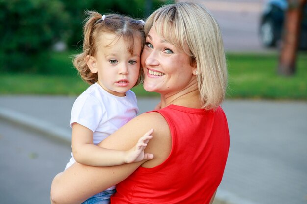 Zdjęcie piękna blondynka mama w czerwonej koszulce z córką. portret grupowy