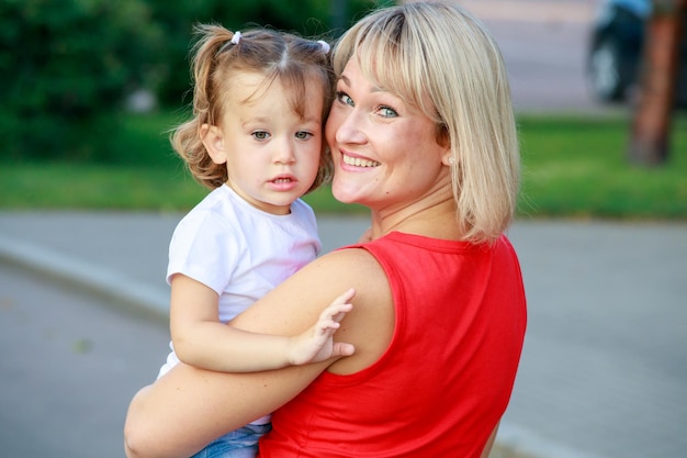 Piękna blondynka mama w czerwonej koszulce z córką. portret grupowy