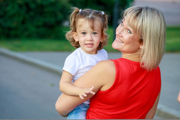 Piękna blondynka mama w czerwonej koszulce z córką. portret grupowy