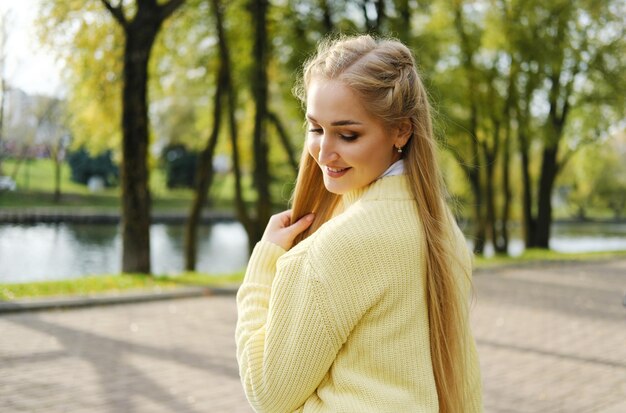 Piękna blondynka pozuje do kamery w jesiennym parku Zdjęcie poziome