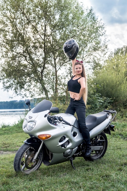 Zdjęcie piękna blondynka siedzi na motocyklu