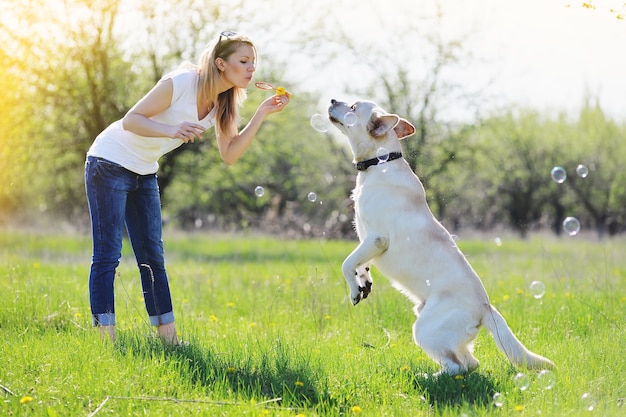 Piękna blondynka spaceruje z labradorem w parku na wiosnę.