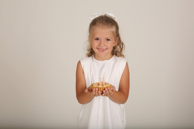 piękna blondynka w białej sukience trzyma w rękach kawałek tortu urodzinowego