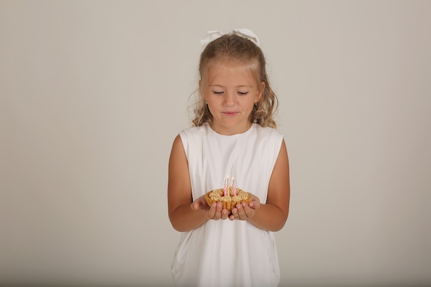 piękna blondynka w białej sukience trzyma w rękach kawałek tortu urodzinowego