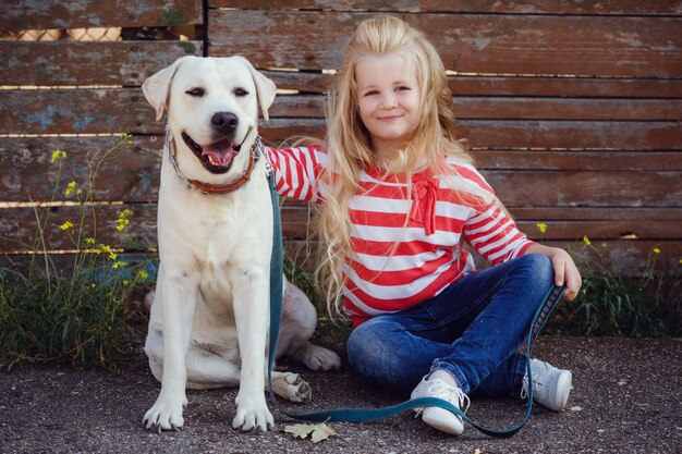 Piękna blondynki dziewczyna bawić się z jej psem. Portret na zewnątrz. seria