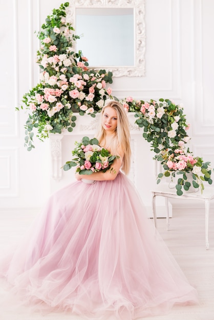 Piękna blondynki dziewczyna w długiej miękkiej purpurowej sukni kwiatów pozować. koncepcja perfum, mody i urody