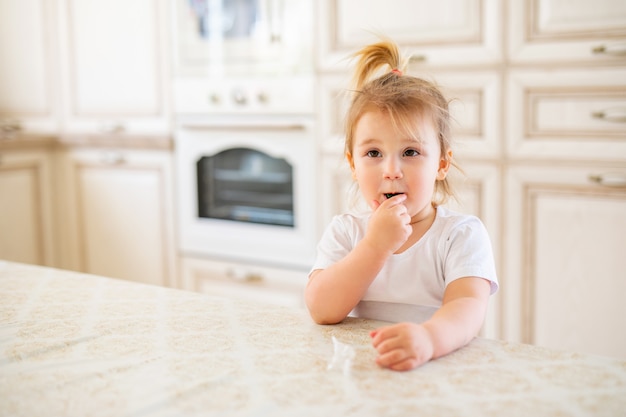 Piękna blondynki dziewczynka ma śniadanie w kuchni. Śmieszne twarze