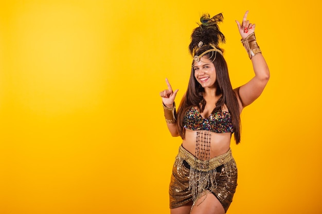 Piękna brazylijska kobieta w złotych karnawałowych ubraniach tańczy, ciesząc się i imprezując