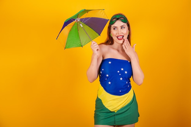 Piękna brazylijska rudowłosa w karnawałowych strojach z flagą Brazylii i kolorowym parasolem