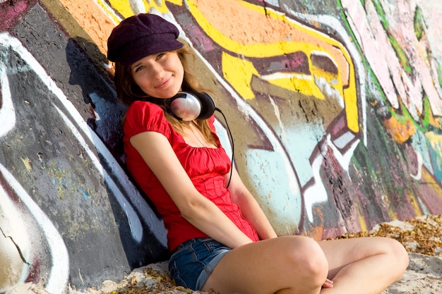 Piękna brunetka dziewczyna ze słuchawkami i graffiti na ścianie