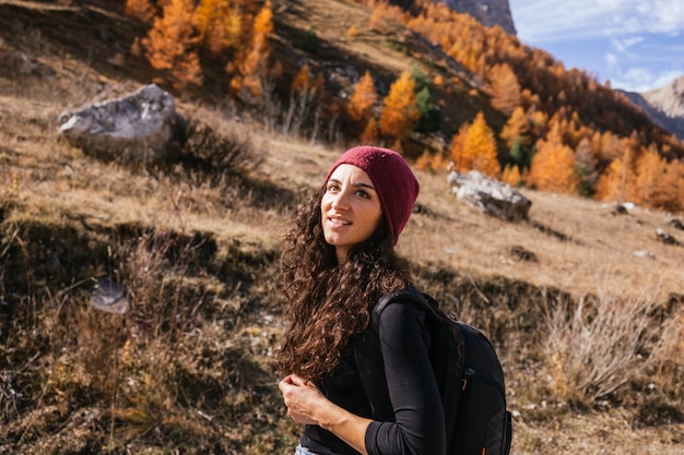 Piękna brunetka dziewczynka kaukaski z długimi kręconymi włosami spacery po górach ubrana w czerwoną wełnianą czapkę
