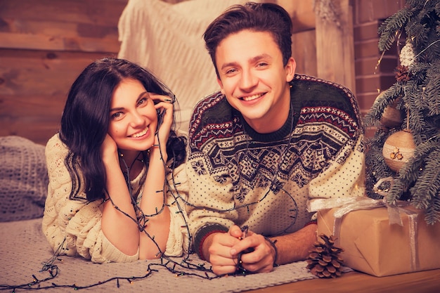 Piękna brunetka kaukaski romantyczna para kochająca się w przytulnych ciepłych swetrach w kabinie w wigilię bożego narodzenia