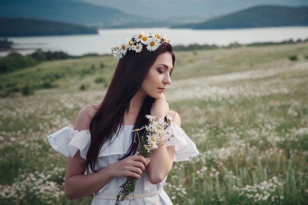 Piękna brunetka kobieta cieszy się wiosną w polu stokrotek