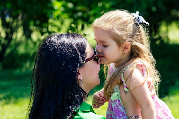 Piękna brunetka kobieta obejmuje dzieci (córkę) w letnim parku