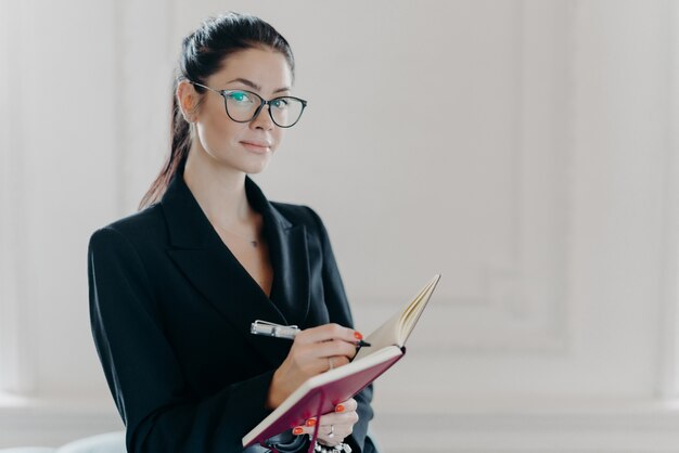 Piękna brunetka kobieta pisze w notatniku