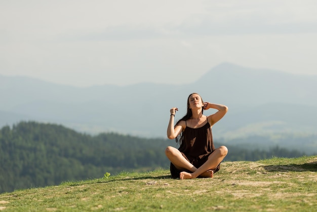 Piękna brunetka kobieta siedzi w pozie lotosu w Karpatach i robi medytację