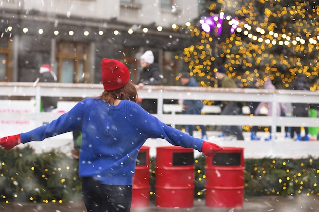 Zdjęcie piękna brunetka kobieta zabawy na targach bożonarodzeniowych podczas opadów śniegu. miejsce na tekst