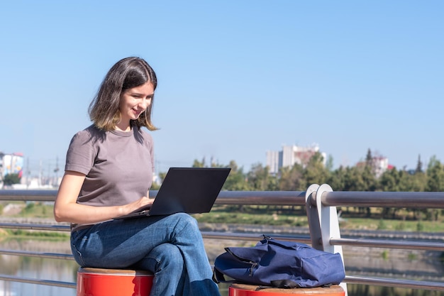 Piękna brunetka studentka w okularach używa laptopa na ulicy Piękna studentka używa laptopa