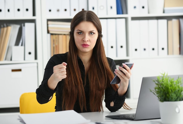 Piękna brunetka uśmiechnięta bizneswoman trzyma telefon komórkowy w ramieniu