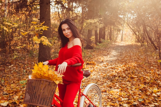 Piękna brunetka w lesie jesienią z rowerem