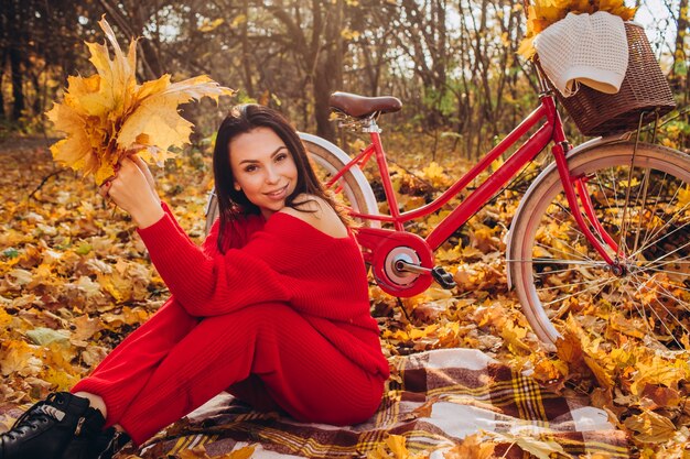 Piękna brunetka w lesie jesienią z rowerem