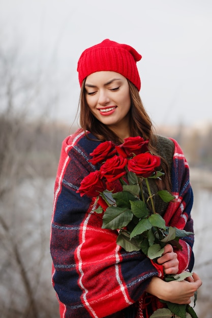Piękna brunetka z bukietem czerwonych róż w dłoniach