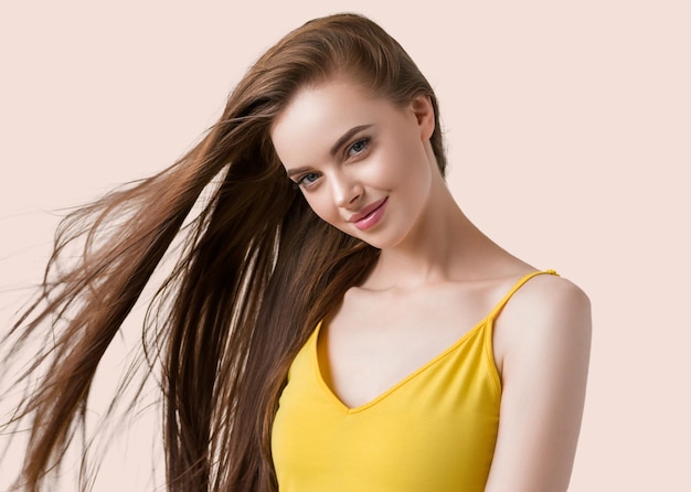 Piękna brunetka z długimi gładkimi włosami w żółtej sukience naturalny portret. Kolor tła. Różowy