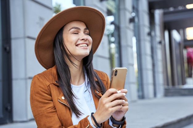 Piękna brunetka z zamkniętymi oczami używająca smartfona