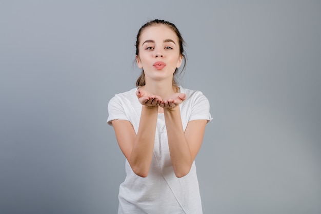 Piękna Brunetki Dziewczyna Flirtuje Dmuchać Buziaka Odizolowywającego Nad Popielatym