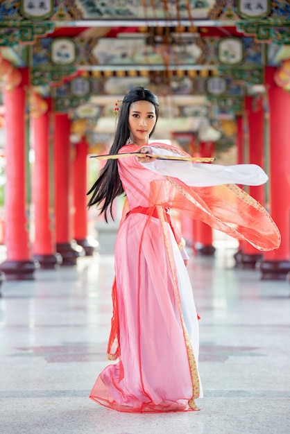 Piękna chińska kobieta z tradycyjnym garniturze z ciosem w dłoniach.