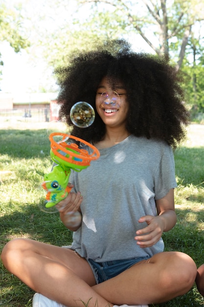 Zdjęcie piękna czarna nastolatka bawiąca się bańkami mydlanymi