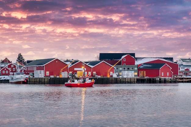 Piękna czerwona wioska rybacka rorbuer i łódź rybacka na wybrzeżu o zachodzie słońca w mieście Reine Lofoty Norwegia