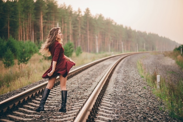 Zdjęcie piękna dancingowa dziewczyna z kędzierzawym naturalnym włosy cieszy się naturę w lesie na kolei