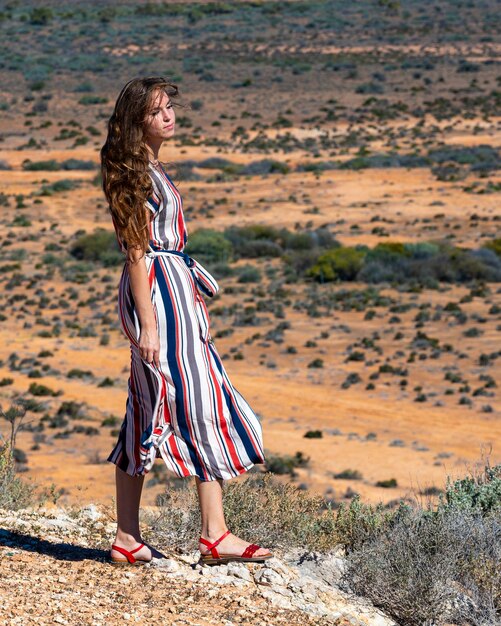 piękna długowłosa dziewczyna stoi na szczycie wzgórza pośrodku pustkowia w zachodniej australii