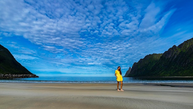 piękna długowłosa dziewczyna w żółtej sukience spaceruje po słynnej plaży ersfjordstranda, senja, norwegia