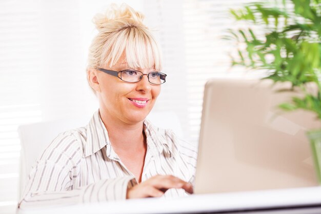 Piękna dojrzała Biznesowa kobieta pracuje na laptopie w biurze.