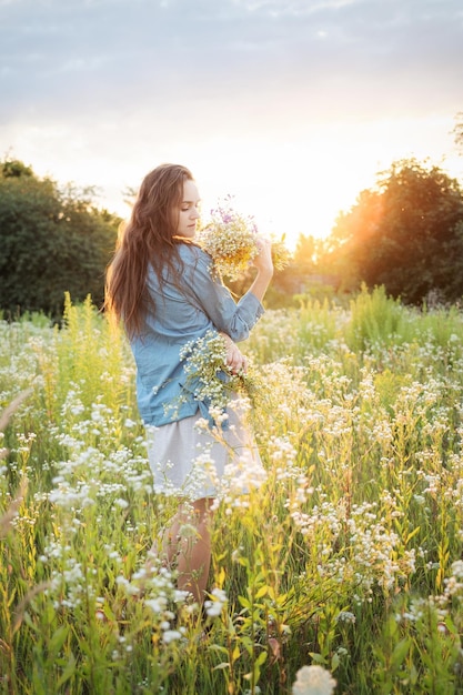 Piękna dziewczyna chodząca po polu w lecie z polnych kwiatów