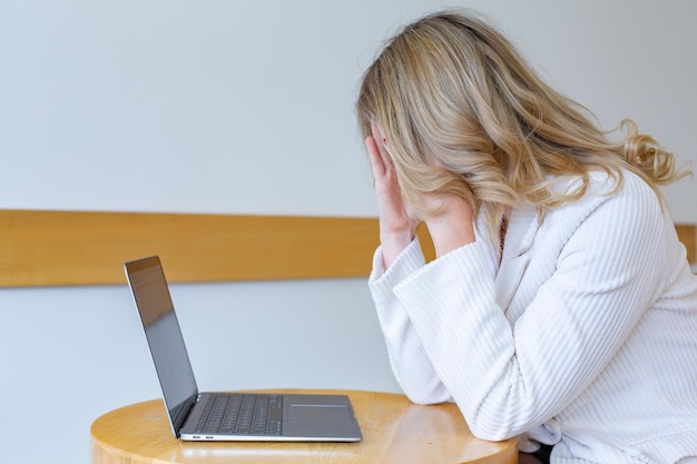 Piękna dziewczyna freelancer czuje się zmęczona i zestresowana podczas korzystania z laptopa i pracy zdalnej.