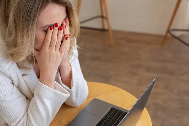 Piękna dziewczyna freelancer czuje się zmęczona i zestresowana podczas korzystania z laptopa i pracy zdalnej.