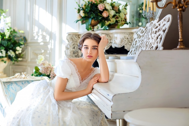 piękna dziewczyna gra na pianinie, w pięknej sukience we wnętrzu