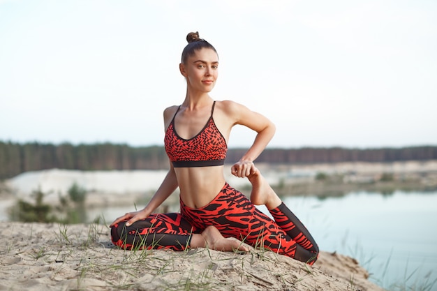 Piękna dziewczyna kaukaski w jasny czerwony sportowej zrobić pozycję jogi, rozciągając się na charakter