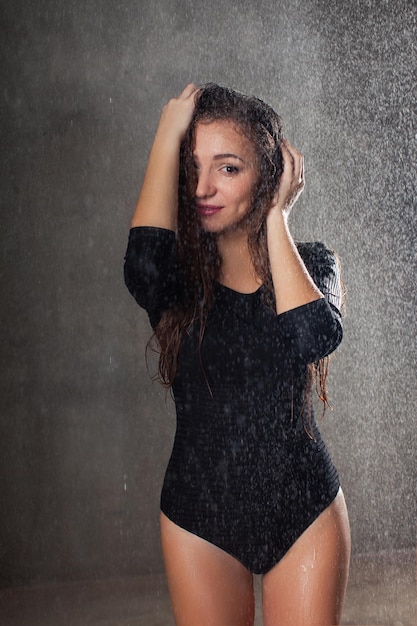 Piękna dziewczyna mokra w deszczu na ciemnym tle